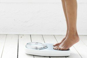 Side profile of the legs of a woman standing on a weighing scale